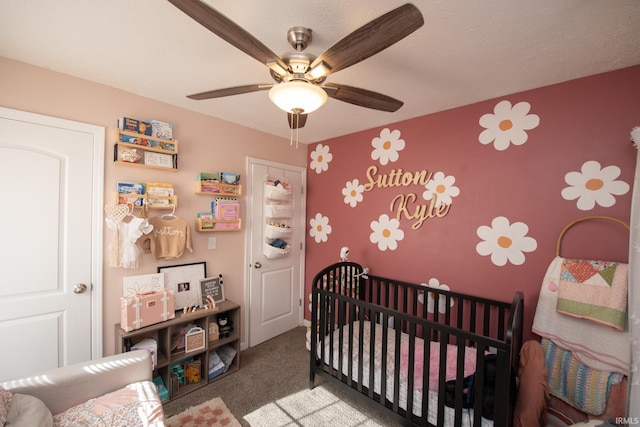 bedroom featuring carpet, a crib, and ceiling fan