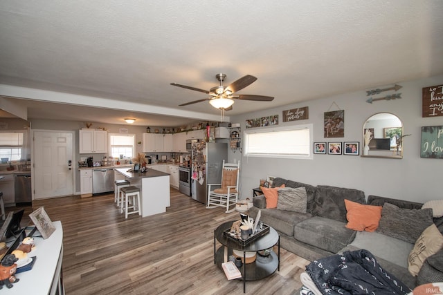 living area featuring arched walkways, ceiling fan, and dark wood-style floors