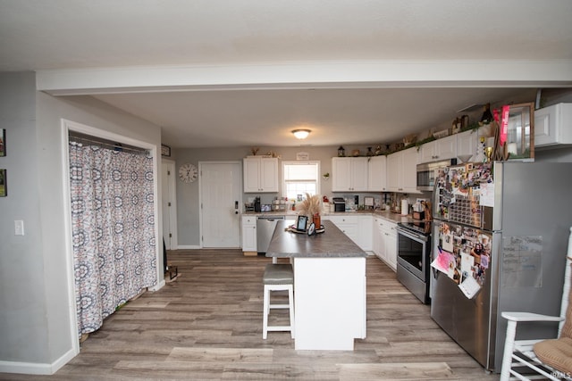 kitchen featuring appliances with stainless steel finishes, a breakfast bar, light wood-style floors, white cabinetry, and baseboards