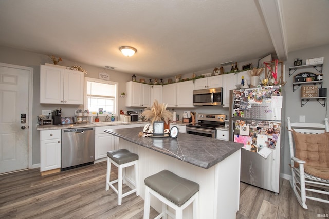 kitchen featuring white cabinets, appliances with stainless steel finishes, a sink, and light wood-style floors