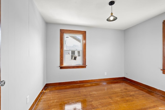 spare room with baseboards and hardwood / wood-style floors