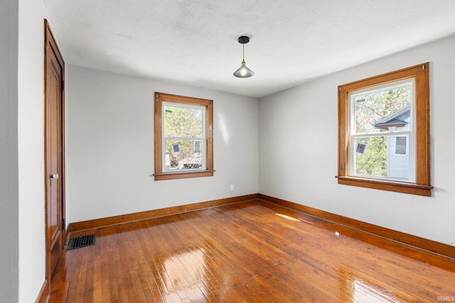 unfurnished room with visible vents, baseboards, and dark wood-style floors