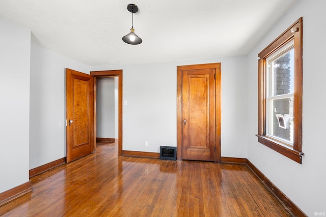 unfurnished bedroom featuring wood-type flooring, baseboards, and visible vents