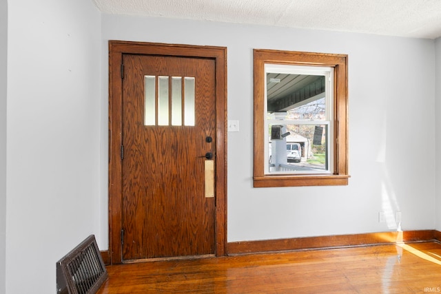 foyer with baseboards, visible vents, and wood finished floors
