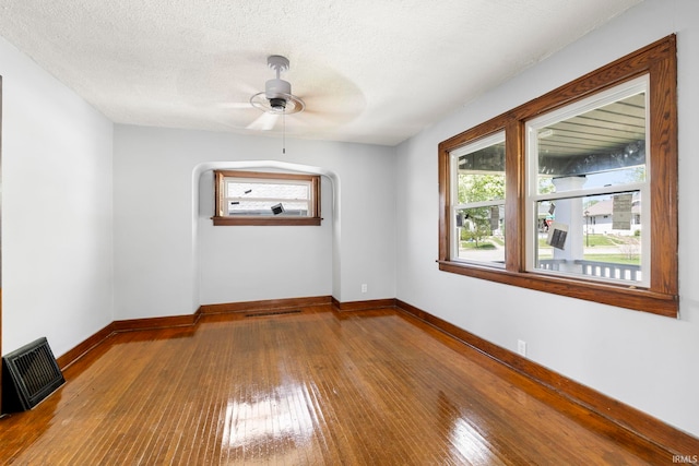 unfurnished room with a ceiling fan, baseboards, visible vents, and hardwood / wood-style floors
