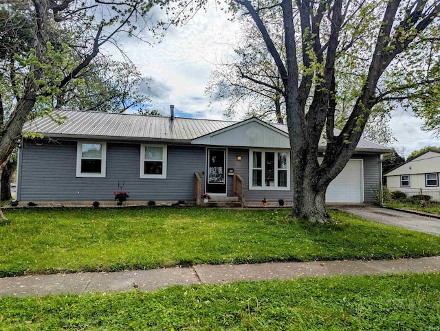 ranch-style house featuring an attached garage, aphalt driveway, a front yard, and metal roof