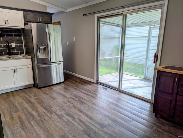 kitchen featuring wood finished floors, stainless steel fridge, a sink, and tasteful backsplash