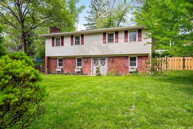 colonial inspired home featuring brick siding, a front lawn, fence, and a chimney