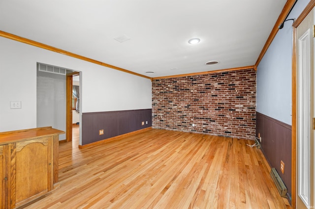 unfurnished room with light wood-style floors, wainscoting, crown molding, and baseboard heating