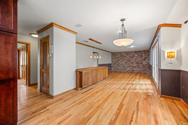kitchen featuring baseboards, light wood-style flooring, brick wall, and hanging light fixtures