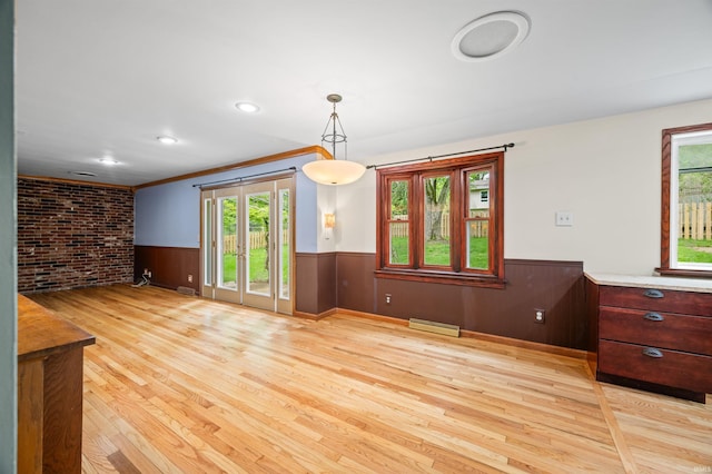 interior space featuring a wainscoted wall, a baseboard heating unit, light wood finished floors, and a wealth of natural light