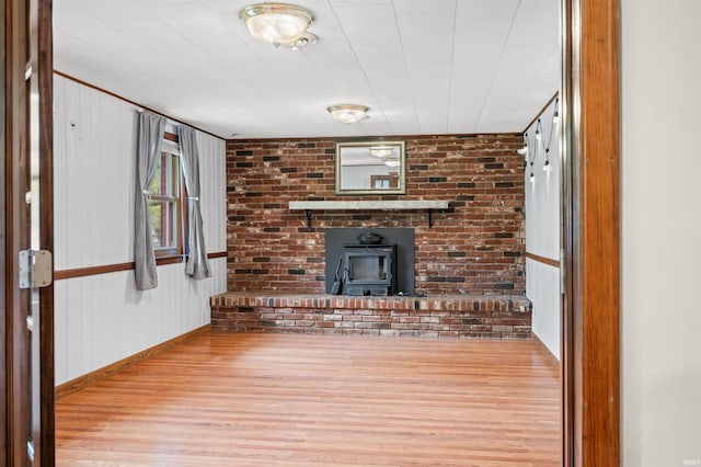 unfurnished living room featuring baseboards, wood finished floors, and a wood stove