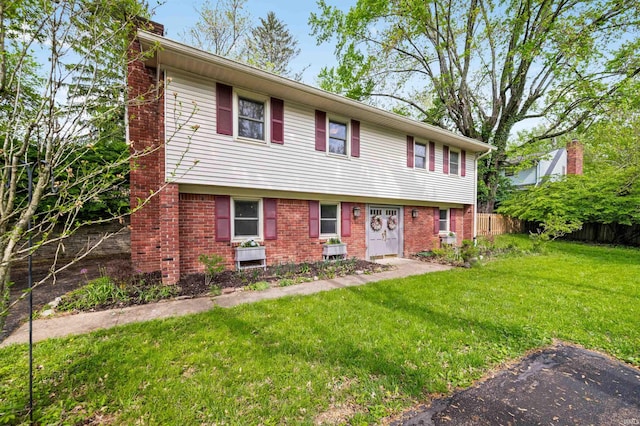 colonial home with brick siding, fence, a front yard, and a chimney