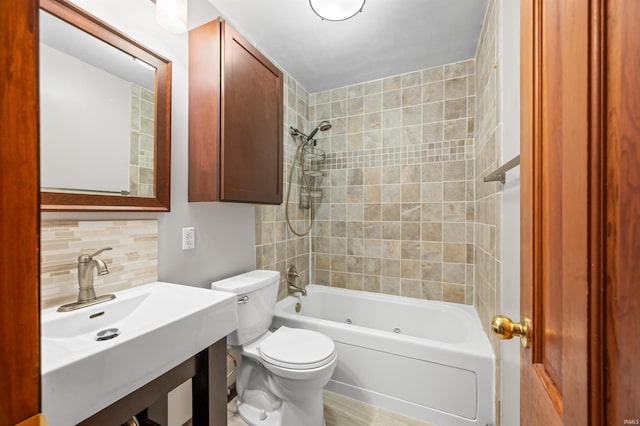 bathroom featuring a sink, decorative backsplash, toilet, and  shower combination