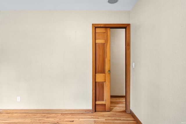 unfurnished room featuring baseboards and light wood-type flooring