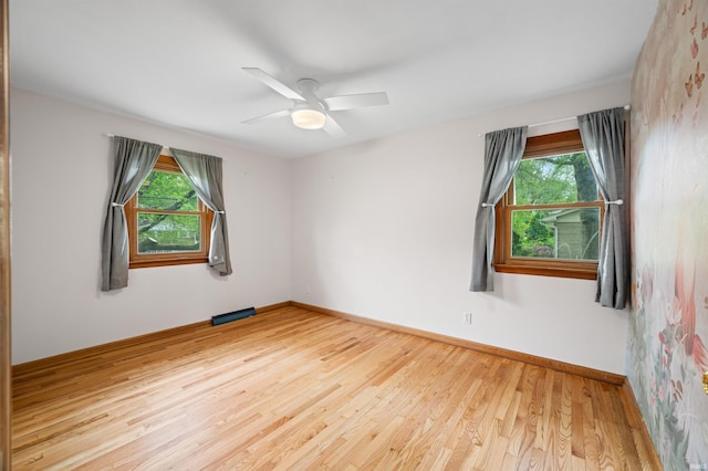 unfurnished room featuring baseboards, plenty of natural light, and wood finished floors