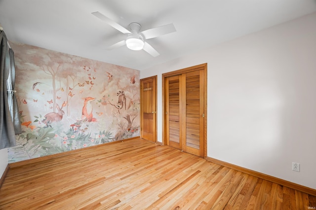 unfurnished bedroom with baseboards, ceiling fan, wood finished floors, and a closet