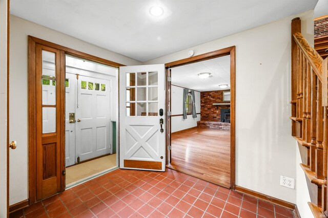 foyer featuring dark tile patterned floors, baseboards, and stairs