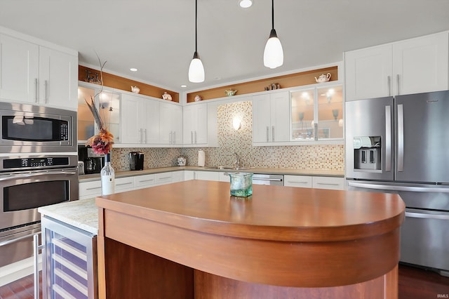 kitchen with a sink, decorative backsplash, white cabinets, and stainless steel appliances