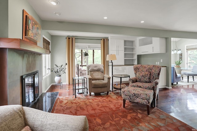living area with a glass covered fireplace, plenty of natural light, and dark wood-type flooring