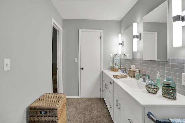 bathroom with double vanity, baseboards, decorative backsplash, and a sink