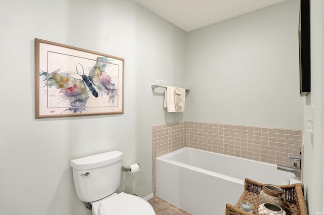 full bath featuring baseboards, a garden tub, and toilet