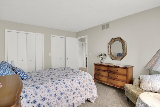 bedroom featuring light colored carpet, multiple closets, and visible vents