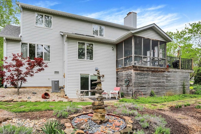 rear view of property with central AC, a chimney, and a sunroom