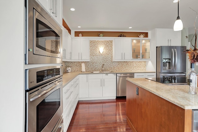 kitchen featuring glass insert cabinets, white cabinetry, tasteful backsplash, a sink, and appliances with stainless steel finishes