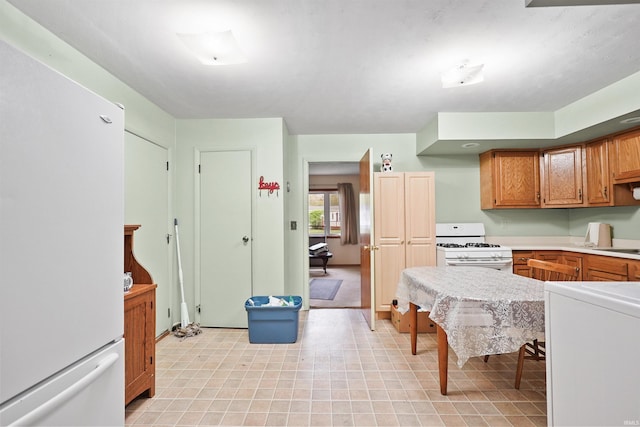 kitchen with white appliances, brown cabinets, a sink, and light countertops