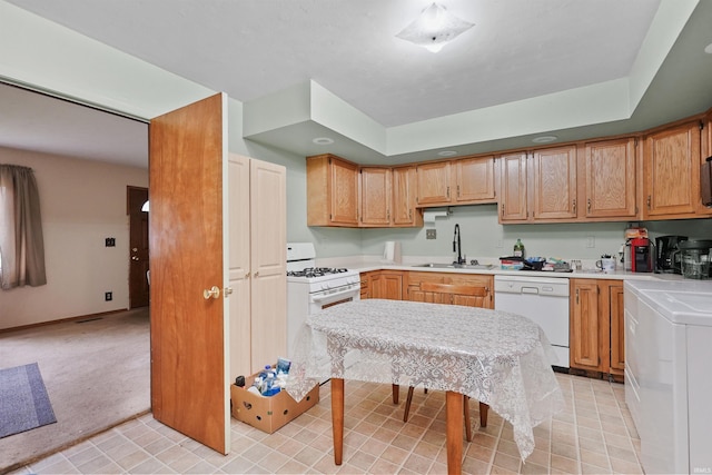kitchen with white appliances, washer / clothes dryer, light colored carpet, light countertops, and a sink