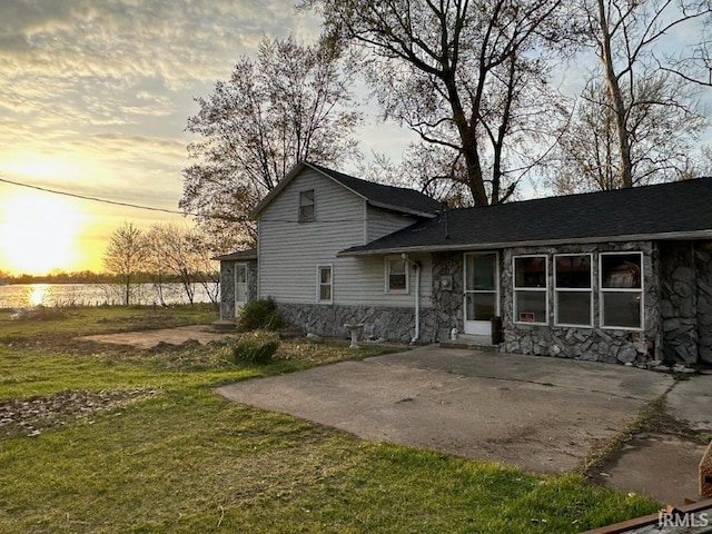 3566 W Sycamore Ln Unit 57, Columbia City, IN 46725 - back of property at dusk featuring a yard, a patio, and stone siding