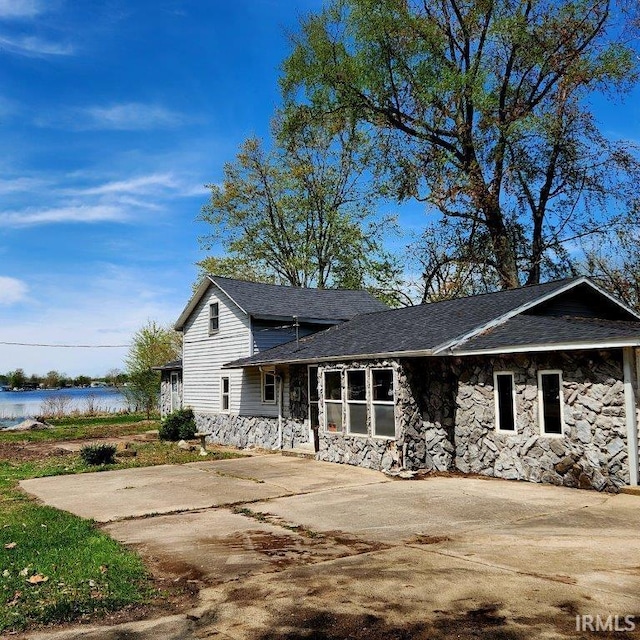 3566 W Sycamore Ln Unit 57, Columbia City, IN 46725 - view of front facade with roof with shingles, a water view, and stone siding