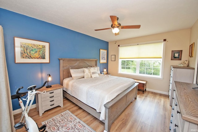 bedroom with baseboards, a ceiling fan, and light wood-style flooring