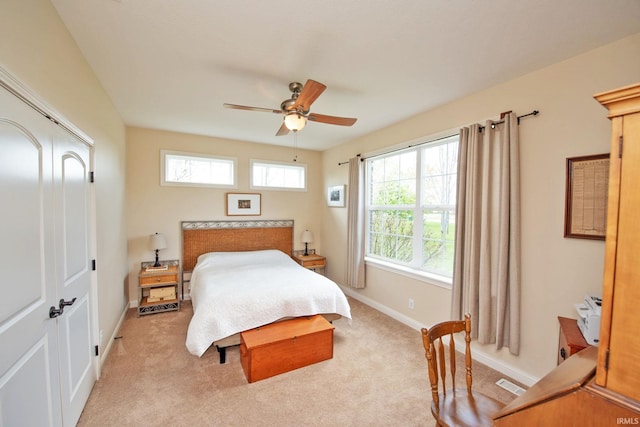 bedroom with baseboards, visible vents, light carpet, and a closet