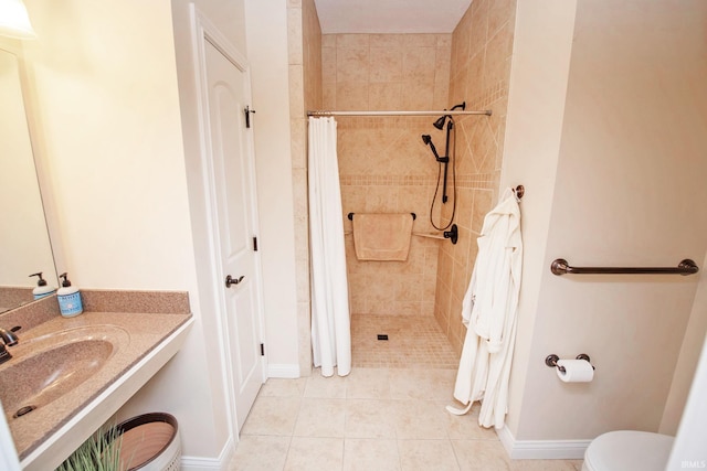 bathroom featuring toilet, tile patterned floors, a tile shower, and vanity