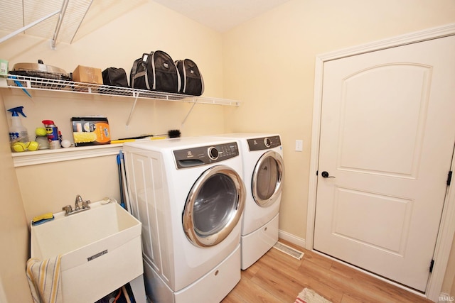 washroom with laundry area, a sink, independent washer and dryer, and light wood-type flooring