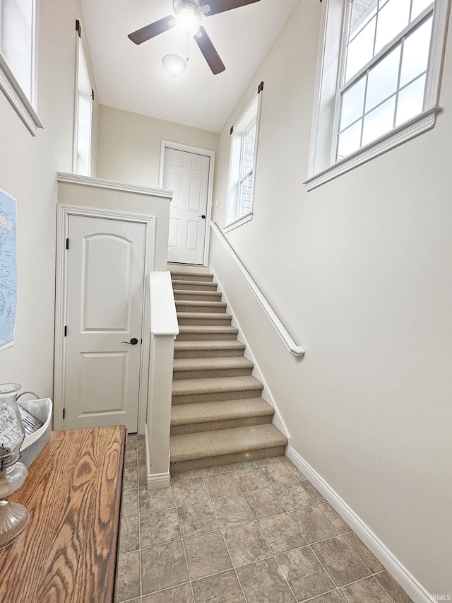 stairway with baseboards and ceiling fan