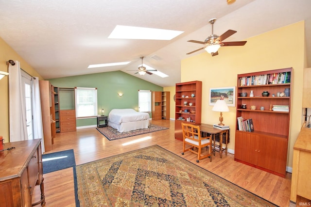 bedroom featuring baseboards, visible vents, light wood finished floors, and lofted ceiling with skylight