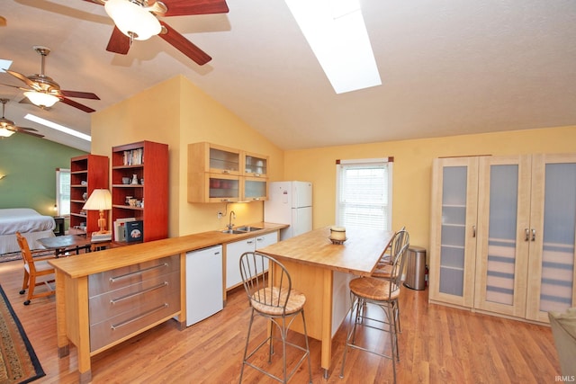 kitchen featuring lofted ceiling with skylight, butcher block counters, and white appliances