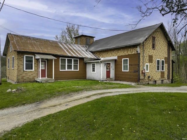 view of front facade with entry steps, metal roof, and a front lawn