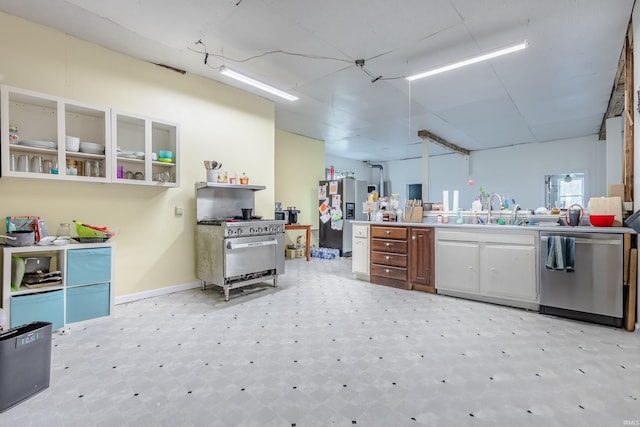 kitchen featuring baseboards, light floors, light countertops, a sink, and appliances with stainless steel finishes
