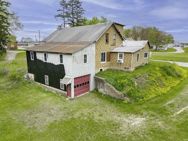 view of side of property with a lawn, driveway, metal roof, and a garage