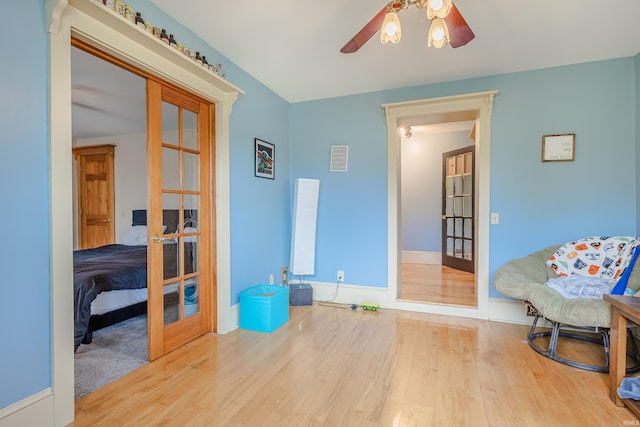 living area featuring baseboards, a ceiling fan, french doors, and wood finished floors