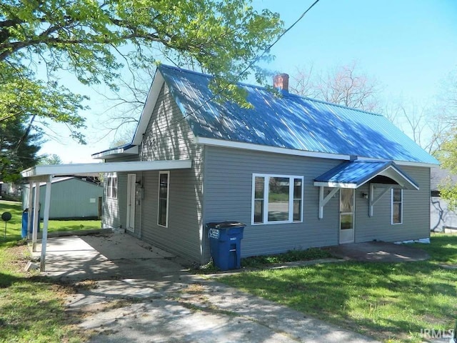 414 17th St, Bedford, IN 47421 - view of front of home with driveway, a chimney, metal roof, a carport, and a front lawn