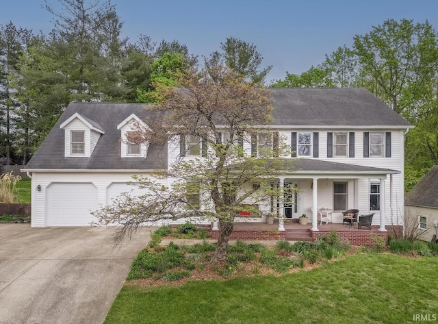 colonial home with a garage, a front yard, a shingled roof, a porch, and driveway