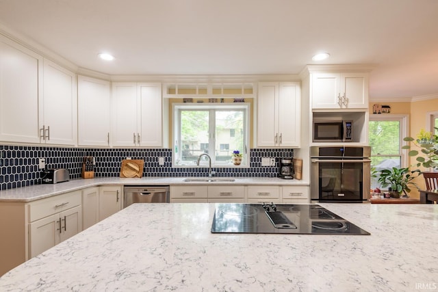 kitchen featuring backsplash, stainless steel appliances, light stone counters, and a sink
