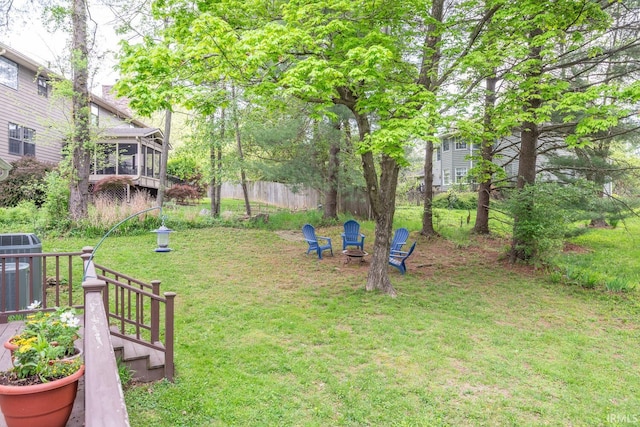 view of yard featuring fence, cooling unit, a sunroom, and an outdoor fire pit