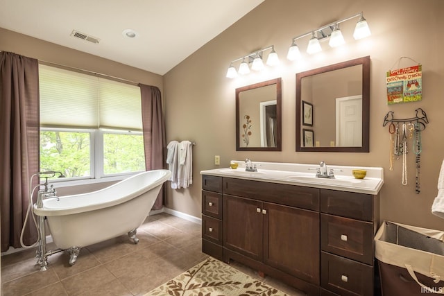 full bath with visible vents, a freestanding bath, a sink, baseboards, and tile patterned floors