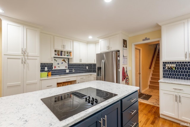 kitchen featuring backsplash, black electric cooktop, stainless steel fridge with ice dispenser, white cabinets, and recessed lighting